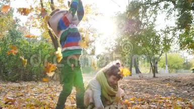 姐姐和哥哥在树的背景上把黄色的叶子扔到空中，在背光下玩耍